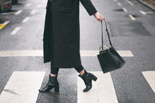 Fashion Blogger Outfit Details. Fashionable Woman Wearing A Black Oversized Coat, Black Jeans, Black Ankle Shoes A Black Trendy Handbag. Detail Of A Perfect Fall Fashion Outfit.

