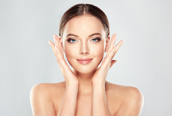 Wall Mural - beautiful young woman with clean fresh skin touch own face . facial treatment . cosmetology , beauty