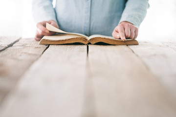 Wall Mural - hands praying with a bible over wooden table