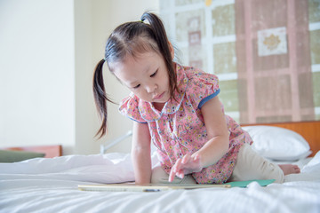 Wall Mural - Little asian girl playing game on tablet computer