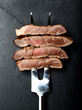 Piece of beef steak on meat fork on black  background