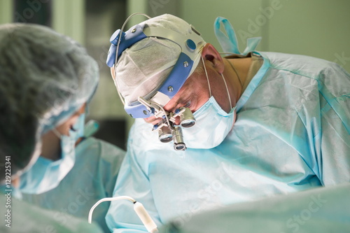 Fotografía Surgeon and his assistant performing cosmetic surgery in hospital operating room