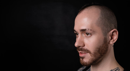 Satisfied male face on black background. Bald man portrait with free spaace for promotion content.