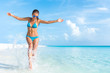 © Maridav - Sexy bikini body woman playful on paradise tropical beach having fun playing splashing water in freedom with open arms. Beautiful fit body girl on luxury travel vacation.
