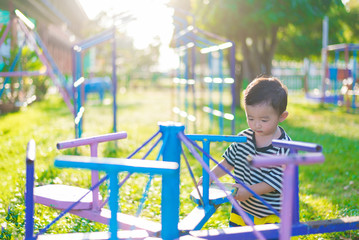 Wall Mural - Sad little Asian kid at the playground under the sunlight in sum