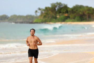 Wall Mural - Man athlete running topless in shorts on beach at sunset. Male runner training cardio alone doing exercise on sand with ocean background. Healthy active lifestyle.