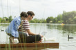 © PhotoAlto - Couple using a laptop while sitting on dock