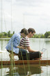 © PhotoAlto - Couple using a laptop while sitting on dock
