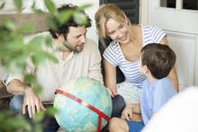 Family Looking At A Globe While Sitting At Home