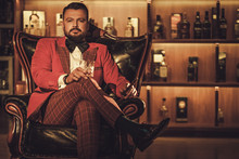 Extravagant Stylish Man With Whisky Glass Sitting On Armchair In