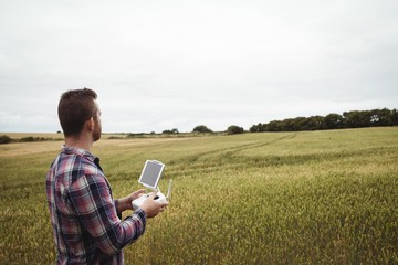 Poster - Farmer using agricultural device while examining in field