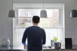 © Maskot - Rear view of man working in kitchen at home