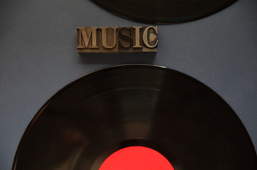 The word music in old metal type with two vinyl recordings on a dark background