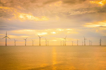 Sunset Offshore Wind Turbine in a Wind farm under construction off the coast of England.