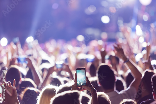Fotografie, Obraz Hand with a smartphone records live music festiva