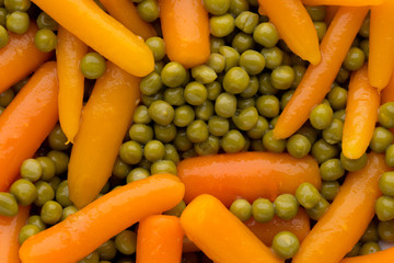 Carrots with green peas vegetable background.