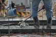 © prachid - Concrete casting work.Worker wearing blue jeans and plastic brown boots leveling concrete work step of the building construction.