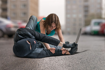 Young woman was attacked by armed thief and is fighting and defending herself. Self defense concept.