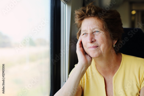 Poster Portrait of beautiful 70 years old woman sitting in the train