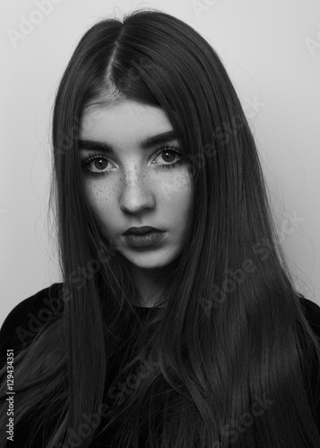 Dramatic black and white portrait of a beautiful lonely girl with freckles isolated on a white Dramatic black and white portrait of a beautiful lonely girl with freckles isolated on a white