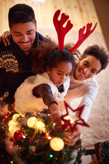 family decorated Christmas tree, parents with little daughter