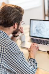 Rear View, young man sitting at her desk and working on a projec