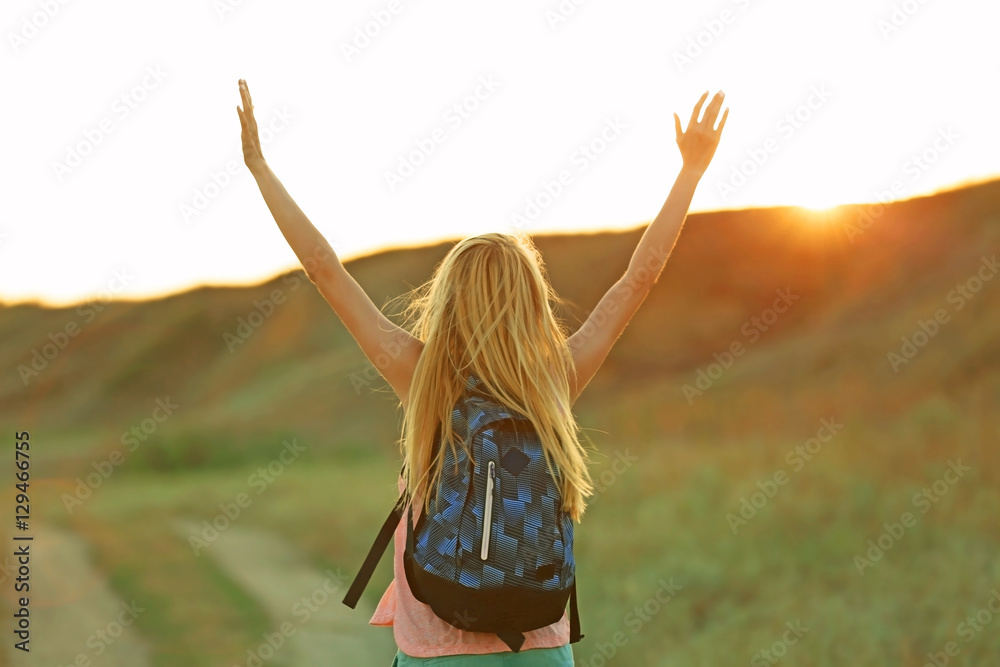 Young woman with raising hands on blue sky background