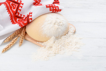 Wall Mural - Ball of raw dough isolated on white wooden table with ears wheat. Copy space. Package. Top view. Russian or Ukrainian Style