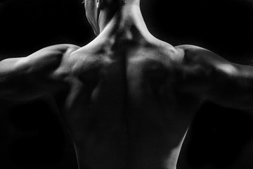 Male fitness model showing muscles in studio with a black backgr