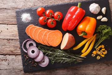 Wall Mural - Fresh vegetables sweet potatoes, peppers, tomatoes, onions, garlic, rosemary and spices closeup. Horizontal top view