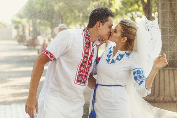 Wall Mural - Rain falls on beautiful wedding couple in Ukrainian embroidered