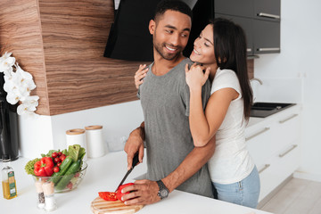 Poster - Happy young couple in the kitchen hugging while cooking.