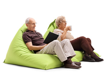 Canvas Print - Elderly man and woman sitting on beanbags