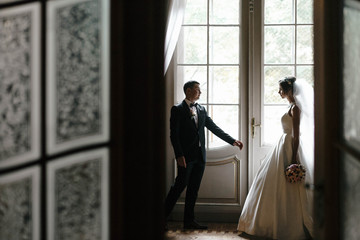 Wall Mural - beautiful bride and groom standing together near a window