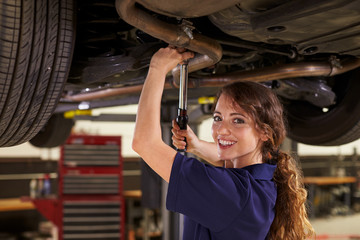 Portrait Of Female Auto Mechanic Working Underneath Car