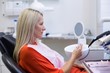 © WavebreakMediaMicro - Patient checking her teeth in mirror