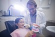 © WavebreakMediaMicro - Dentist showing young patient how to brush teeth