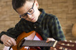 Boy With Glasses Playing Acoustic Guitar in Living Room