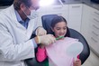 © WavebreakMediaMicro - Dentist assisting young patient while brush teeth