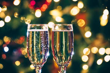 Beautiful two glasses of champagne standing on the table in the background of a blurred room with a decorated Christmas tree and fireplace. Soft focus. Shallow DOF