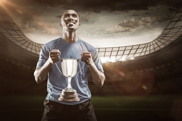 Wall Mural - Composite image 3D of happy athlete holding trophy looking up