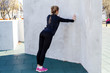 Fitness woman doing push-ups at the wall, back view