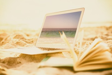 Poster - Composite image of open book and laptop on sand