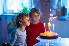 Little Kid Boys Twins Celebrating Birthday And Blowing Candles On Cake