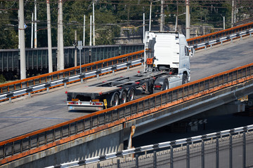 Wall Mural - empty truck on road, rides up over the bridge, industrial infrastructure and railroad in sea port, cargo transportation, delivery and shipping concept