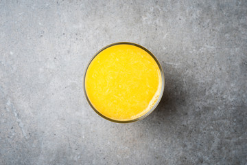 Glass of fresh orange juice on gray stone table