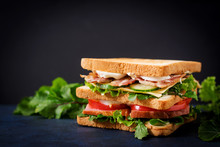 Big Club Sandwich With Ham, Bacon, Tomato, Cucumber, Cheese, Eggs And Herbs On Dark Background