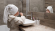 © zdyma4 - Cute little girl in a bath towel on the head and a bathrobe cleaning teeth in the bathroom against the mirror