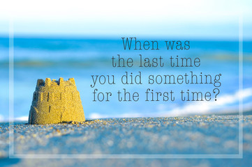 Inspirational motivating quote on blur beach view with sand castle. When was the last time you did something for the first time?