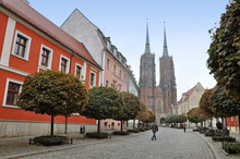 Pedestrian Street With Old Colorful Houses, Decorative Trees And The Gothic Church In Perspective. Wroclaw, Poland.